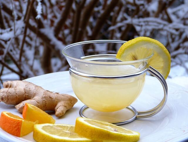 A warm cup of lemon and ginger herbal tea on a table on a frozen and snowing winter day.
