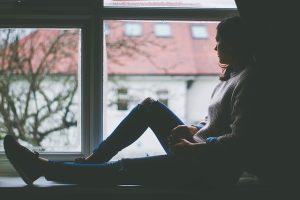 woman looking out window with anxiety